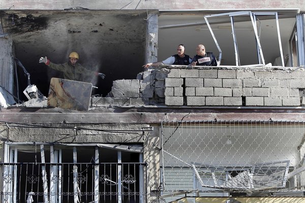 An Israeli soldier throws a bloodstained table from an apartment building hit by a rocket fired from the Gaza Strip on Thursday. The attack killed three people in the southern Israel town of Kiryat Malachi.